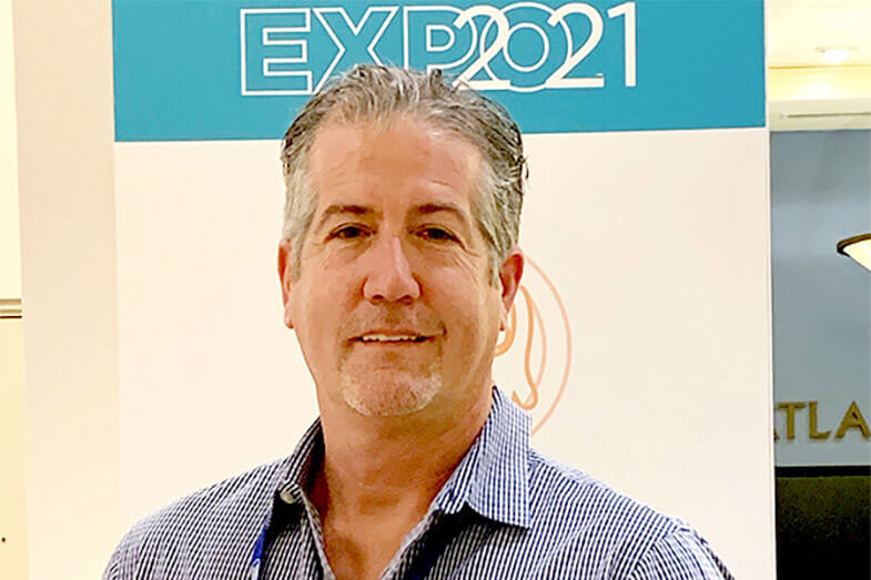 Portrait of a middle-aged man in blue shirt against outdoor background.