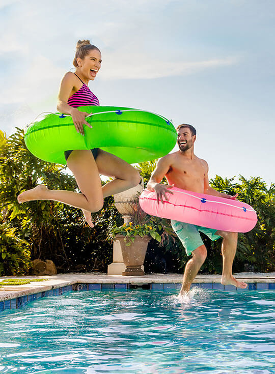 Couple jumping in pool.