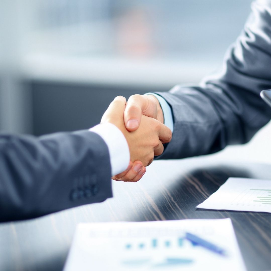 Close-up of two people shaking hands across a desk, symbolizing financing, partnership, or agreement.