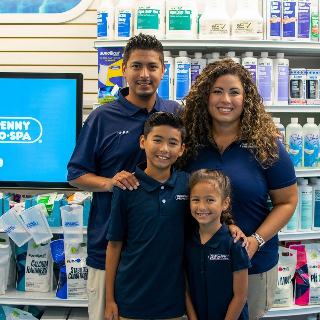 Family of four wearing Pinch A Penny uniforms standing together inside a retail store.