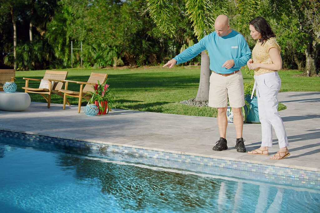 Pool Tech standing by a pool with homeowner