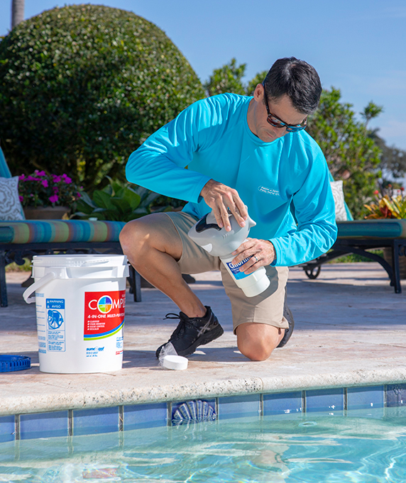 Pool tech adding chlorine to a floating chlorinator