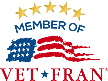 The VetFran logo featuring five gold stars above the words “Member of VetFran.” Below, a stylized American flag with blue and red brushstrokes symbolizes patriotism and support for veterans in franchising.