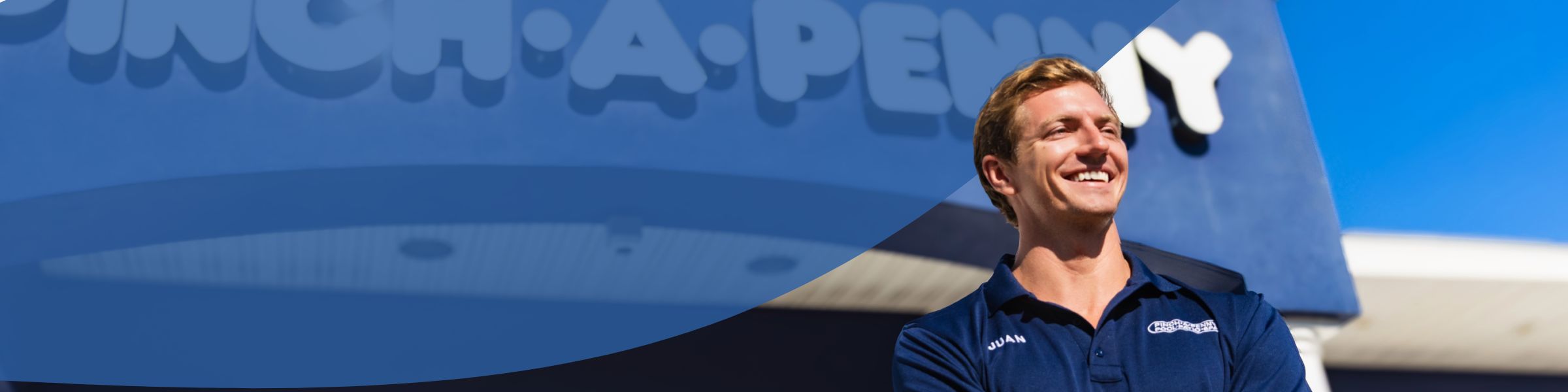 Pinch A Penny employee smiling in front of large storefront sign and blue sky
