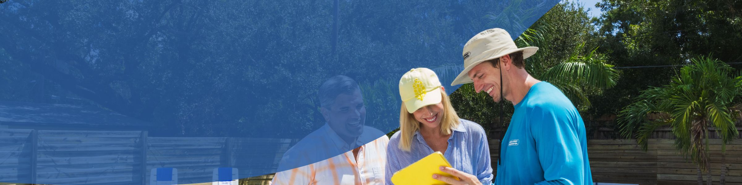 Three adults outdoors reviewing a yellow clipboard near a residential pool