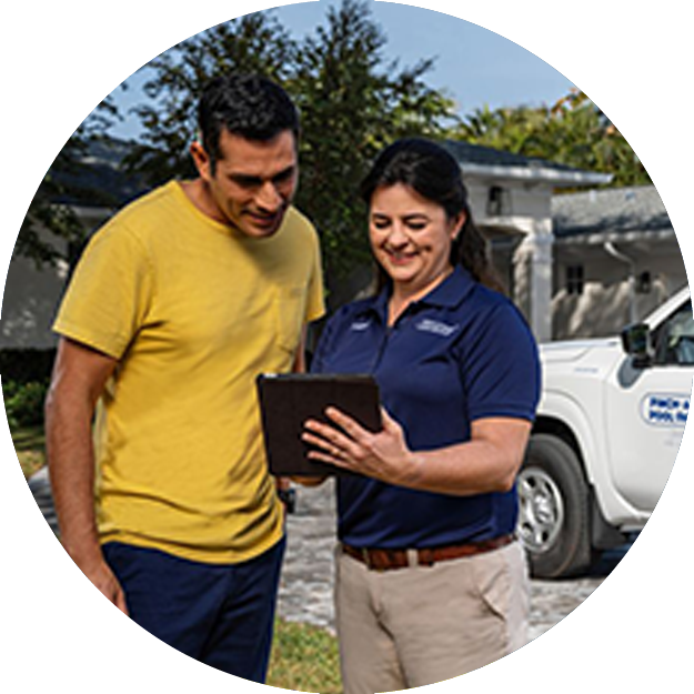 Pinch A Penny pool service technician reviews service details on a tablet with a homeowner beside a branded pool service truck in a residential driveway.